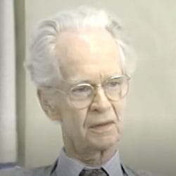Elderly man with gray hair and glasses.